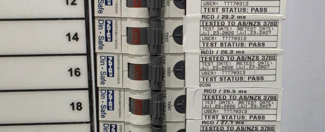 Commercial electrical switchboard with printed RCD trip-time test tags showing millisecond safety pass results